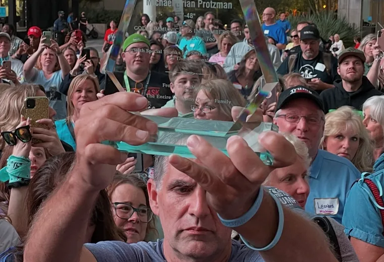 Close object held before a packed outdoor gathering