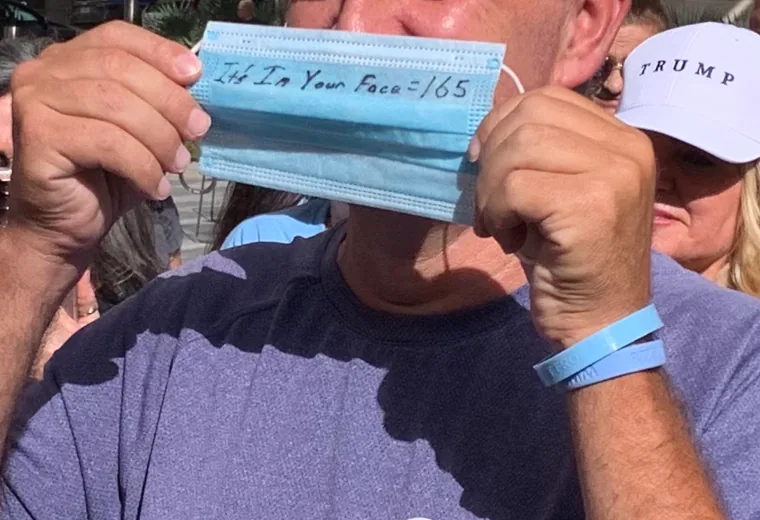Man displaying a handwritten message on a face mask