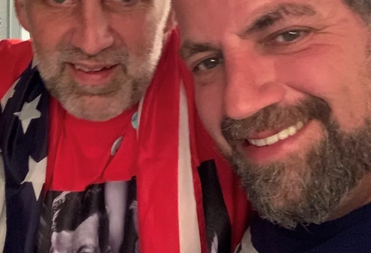 Two attendees posing for a selfie, one draped in a flag