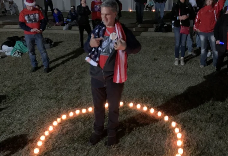 Wide view of people gathered around a candle symbol