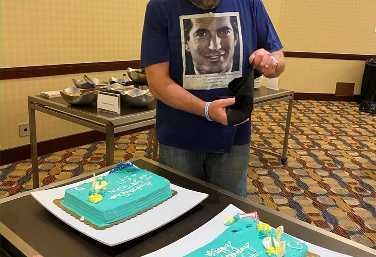 Man standing behind two turquoise birthday cakes